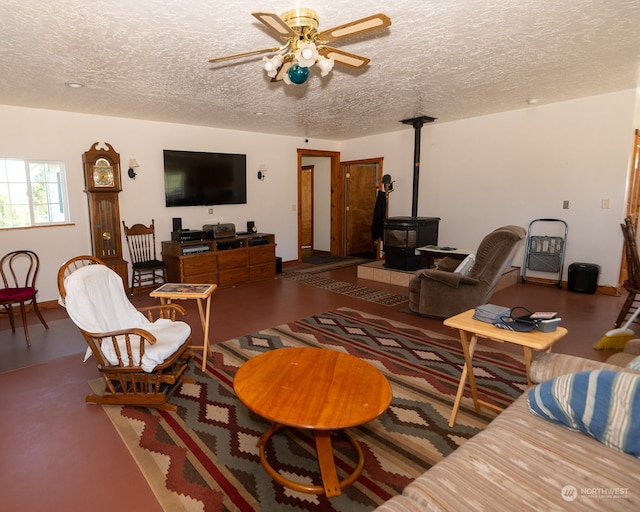 living room featuring ceiling fan, a textured ceiling, hardwood / wood-style flooring, and a wood stove