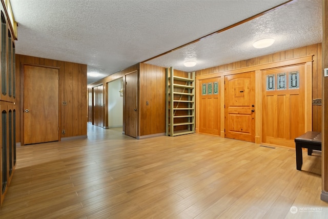 interior space with wooden walls, light hardwood / wood-style flooring, and a textured ceiling