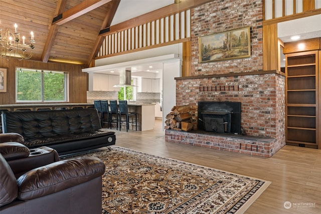 living room featuring brick wall, wood-type flooring, high vaulted ceiling, and a brick fireplace