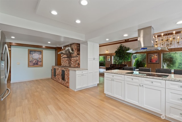 kitchen featuring black electric stovetop, island range hood, white cabinetry, light stone countertops, and light wood-type flooring