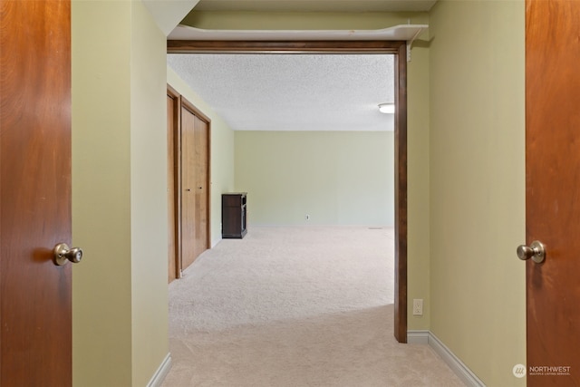 corridor with a textured ceiling and carpet floors