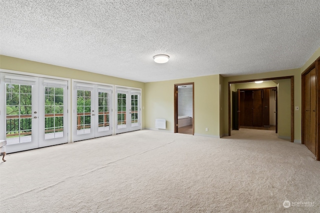 spare room featuring french doors, a textured ceiling, and carpet flooring