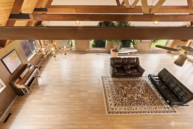 living room with beam ceiling, hardwood / wood-style flooring, wooden walls, and an inviting chandelier