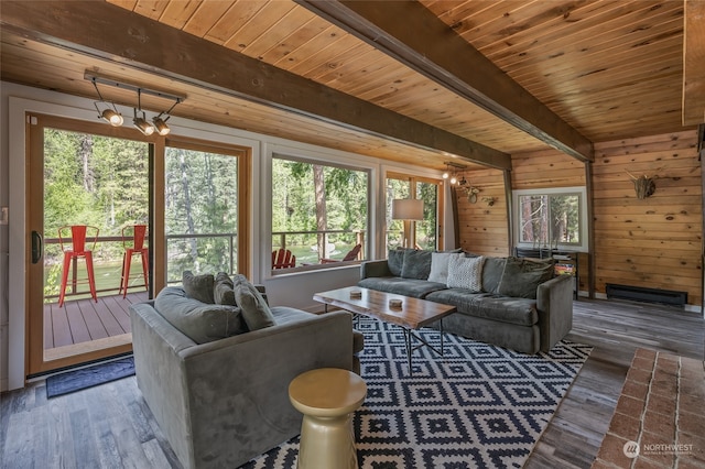 living room with beam ceiling, a notable chandelier, wood walls, and hardwood / wood-style floors