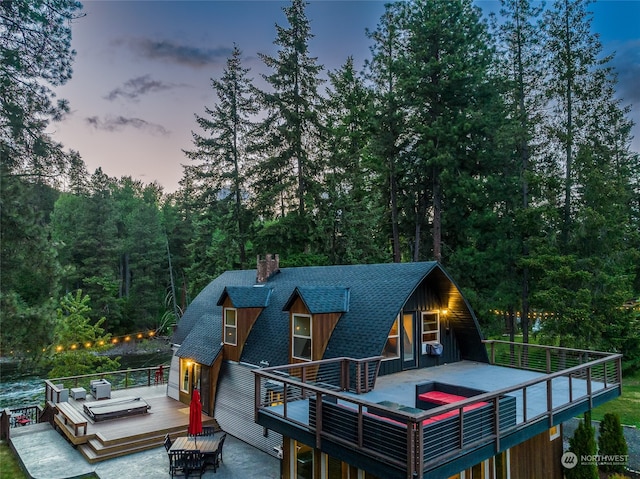 back house at dusk with a deck and an outdoor living space