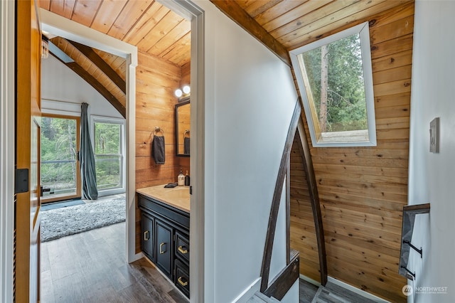 staircase with lofted ceiling with beams, dark hardwood / wood-style flooring, wood walls, and wooden ceiling