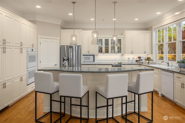 kitchen with a kitchen island, light hardwood / wood-style floors, white appliances, and tasteful backsplash