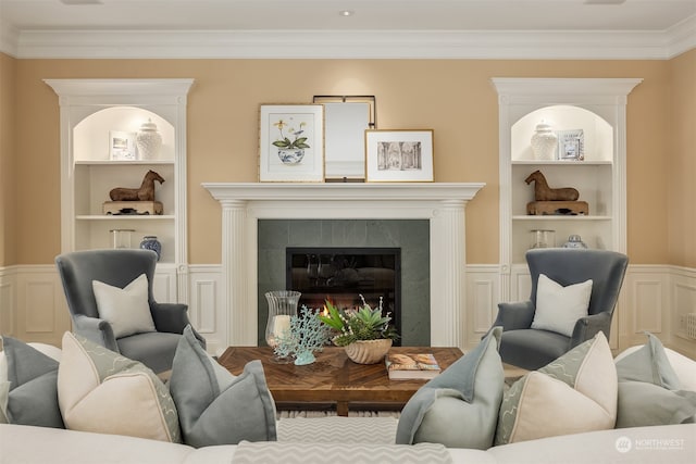 living room featuring crown molding, a tiled fireplace, and built in features