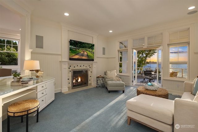 living room with a tile fireplace, a water view, and dark carpet