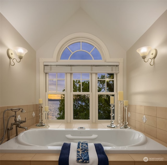 bathroom with tiled tub and lofted ceiling