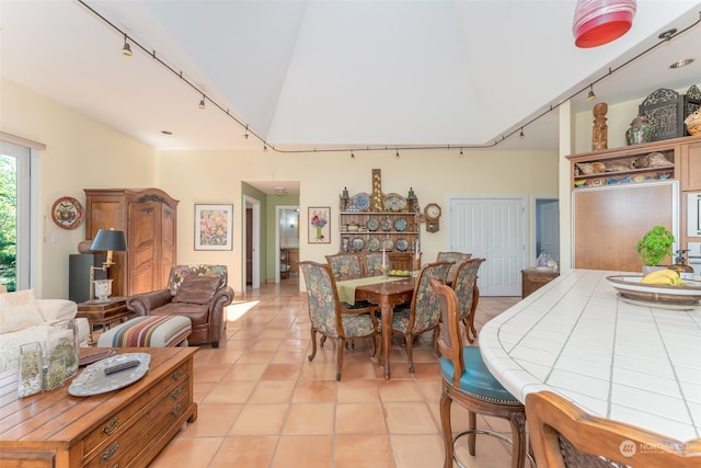 dining space with lofted ceiling, light tile flooring, and rail lighting