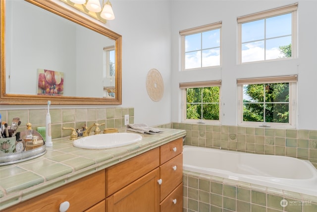 bathroom featuring tasteful backsplash, tiled bath, and vanity