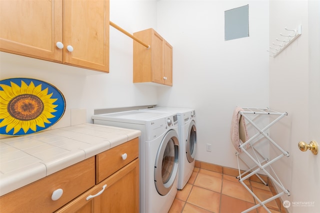 clothes washing area with washer and clothes dryer, cabinets, and light tile floors