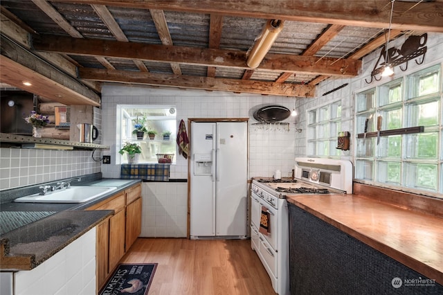 kitchen with beamed ceiling, white appliances, sink, and light hardwood / wood-style flooring