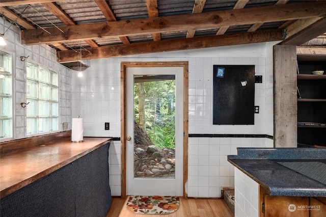 kitchen with tile walls, vaulted ceiling with beams, and light hardwood / wood-style flooring