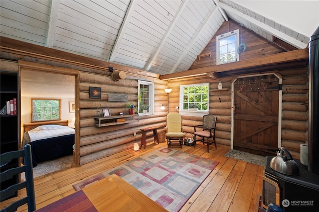 sitting room featuring beam ceiling, plenty of natural light, rustic walls, and wood-type flooring