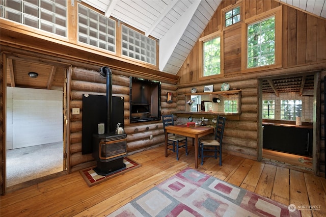 living room featuring high vaulted ceiling, light hardwood / wood-style floors, and a wood stove