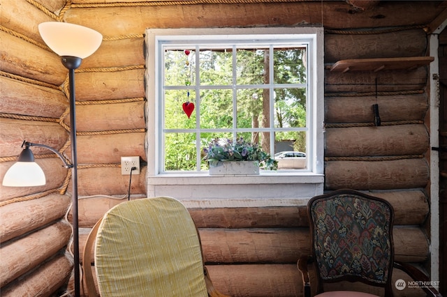 unfurnished room featuring plenty of natural light and log walls