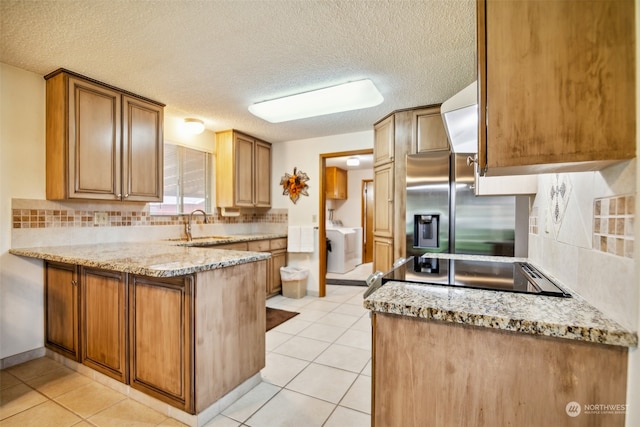 kitchen with kitchen peninsula, light stone counters, backsplash, stainless steel refrigerator with ice dispenser, and light tile flooring