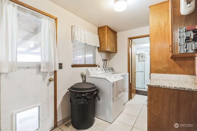 laundry area featuring electric dryer hookup, cabinets, light tile floors, and washing machine and dryer