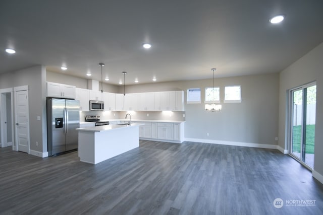 kitchen featuring appliances with stainless steel finishes, white cabinetry, a kitchen island with sink, and pendant lighting