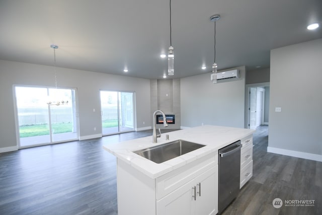 kitchen with pendant lighting, dishwasher, a kitchen island with sink, sink, and white cabinetry