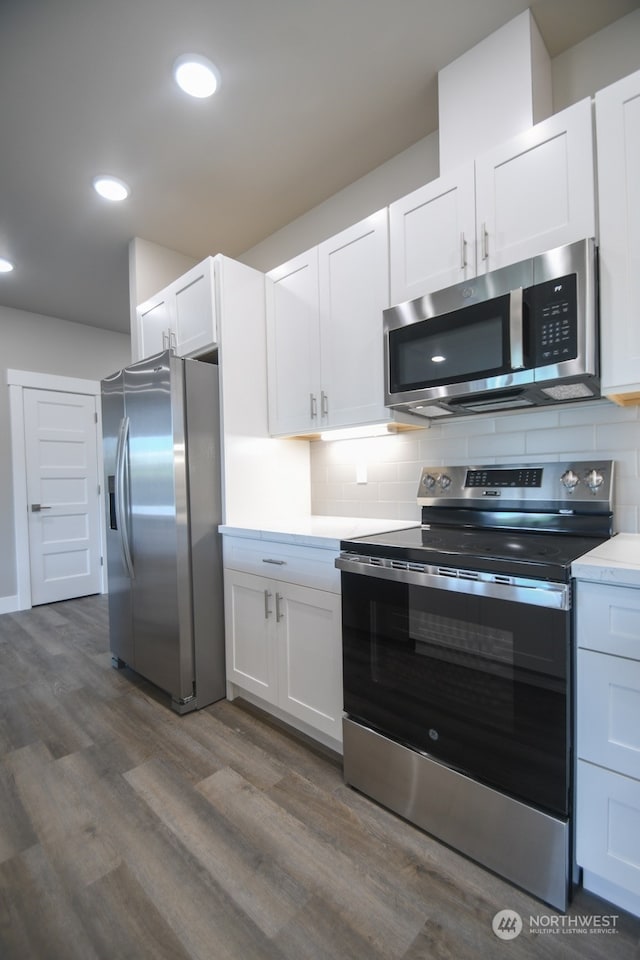 kitchen with white cabinets, dark hardwood / wood-style floors, appliances with stainless steel finishes, and tasteful backsplash