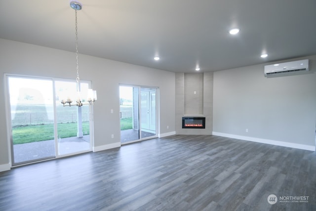 unfurnished living room featuring dark hardwood / wood-style flooring, a fireplace, a wall unit AC, and an inviting chandelier