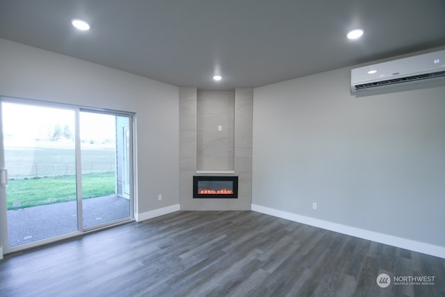 unfurnished living room featuring a wall mounted air conditioner, dark hardwood / wood-style flooring, and a tiled fireplace