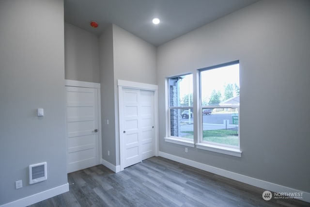 unfurnished bedroom featuring multiple windows, dark hardwood / wood-style flooring, and a closet