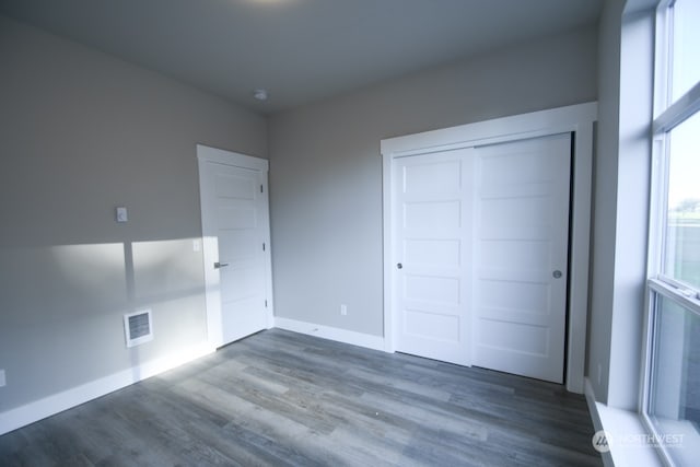 unfurnished bedroom with a closet and dark hardwood / wood-style floors