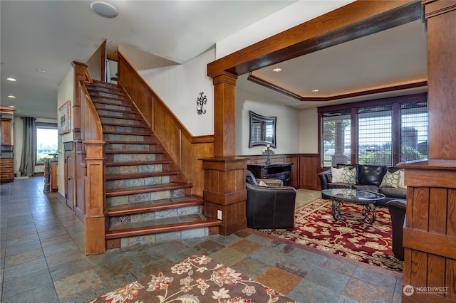 stairway featuring decorative columns, a raised ceiling, and tile patterned floors