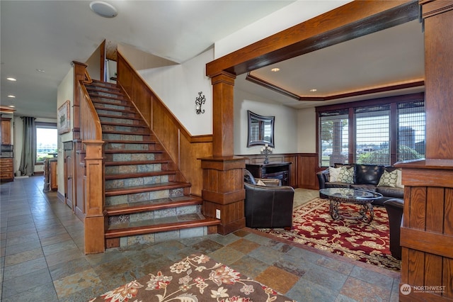 staircase featuring decorative columns and a tray ceiling