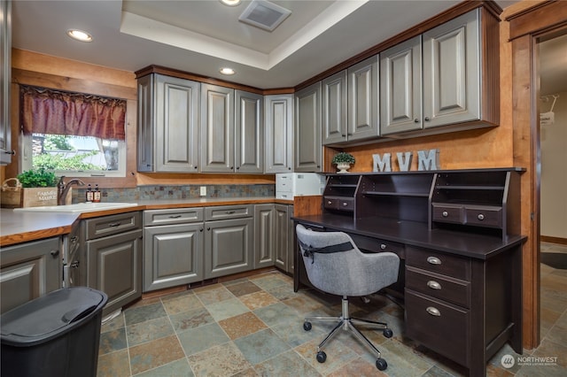 tiled office space with sink and a tray ceiling