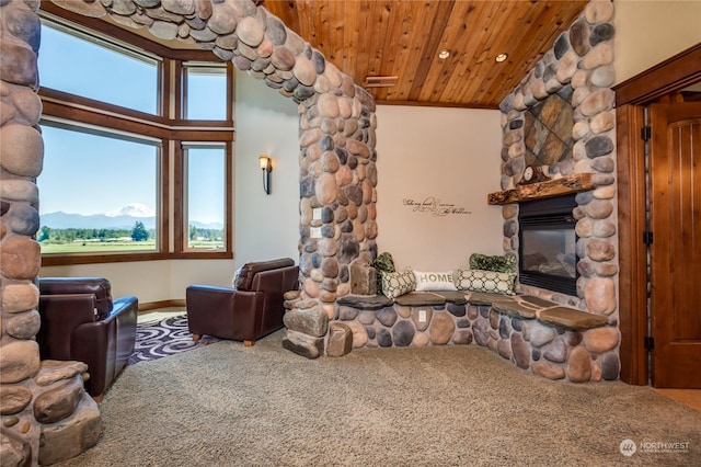 carpeted living room featuring a stone fireplace and wooden ceiling