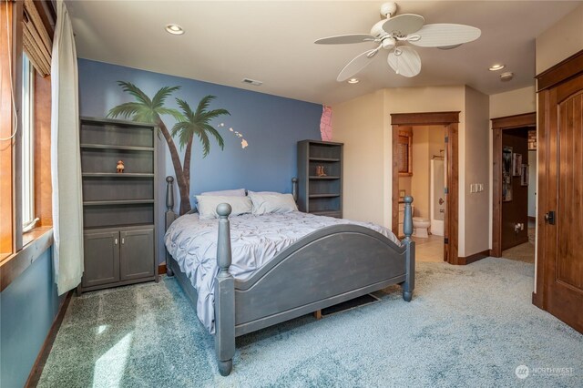 carpeted bedroom featuring connected bathroom, multiple windows, and ceiling fan