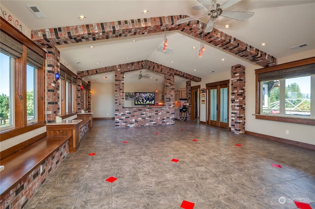 unfurnished living room with brick wall, a wealth of natural light, tile patterned flooring, and ceiling fan