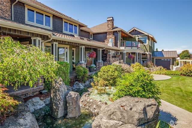 view of front of property featuring a garage, a front lawn, a balcony, and covered porch