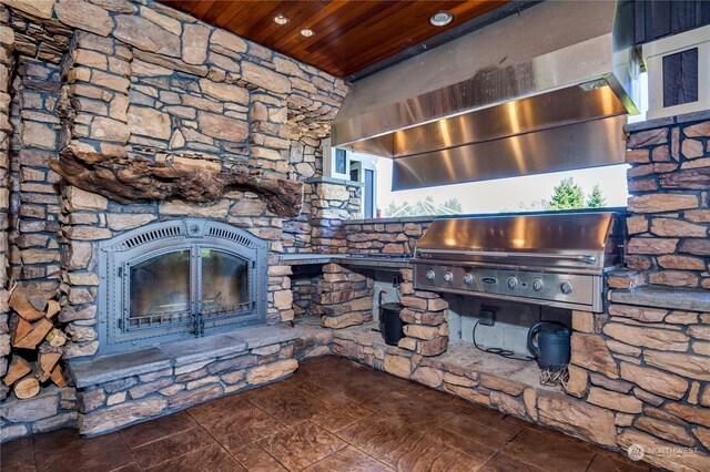 view of patio / terrace featuring a stone fireplace, exterior kitchen, and a grill