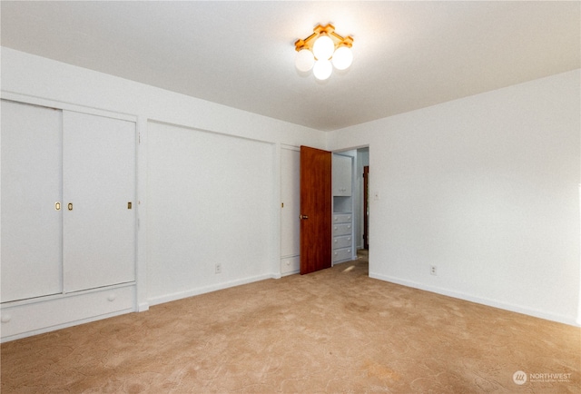 unfurnished bedroom with light colored carpet and two closets