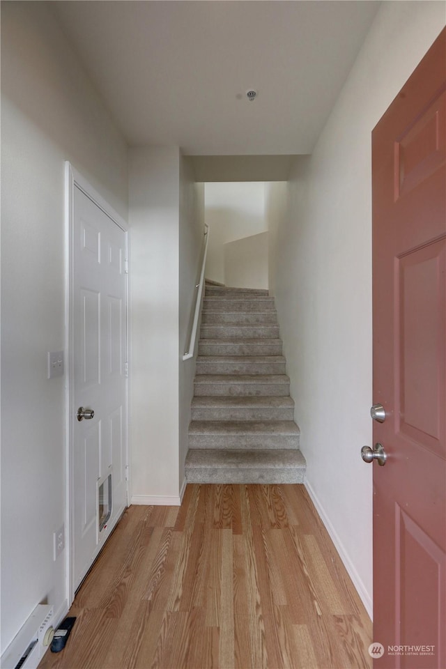 stairs featuring a baseboard heating unit and hardwood / wood-style floors