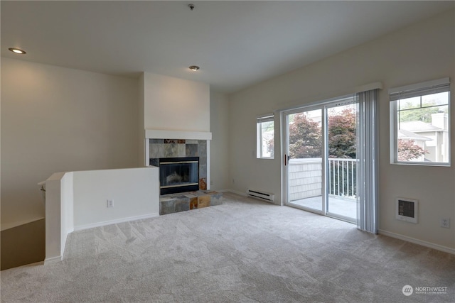 unfurnished living room with a baseboard radiator, a tile fireplace, and light colored carpet