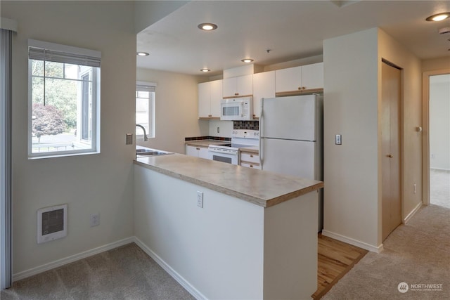 kitchen featuring sink, white cabinetry, white appliances, kitchen peninsula, and light colored carpet