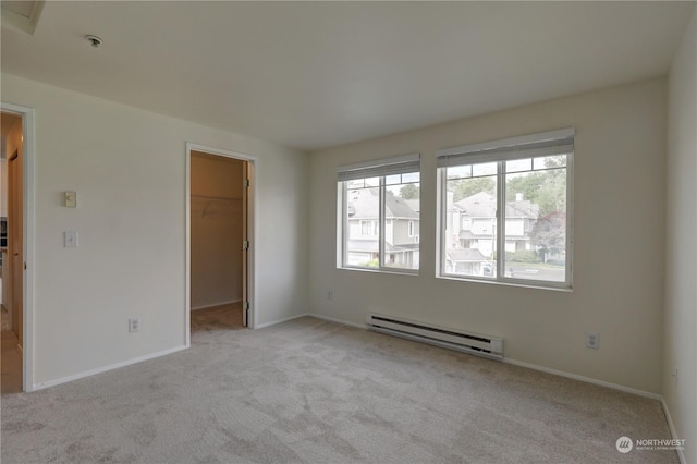 carpeted spare room featuring a baseboard radiator and plenty of natural light