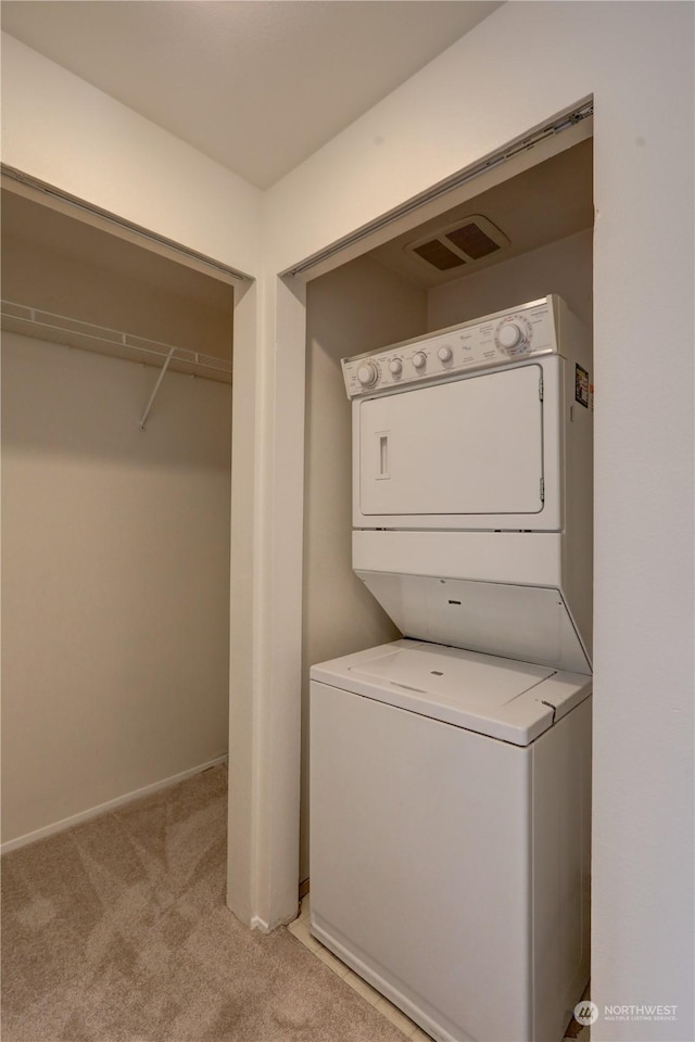 laundry room with light colored carpet and stacked washer and dryer