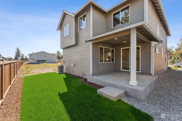 rear view of house with a yard, a patio, and central AC