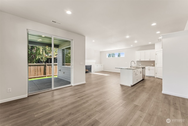 kitchen featuring white cabinets, an island with sink, light hardwood / wood-style flooring, and plenty of natural light