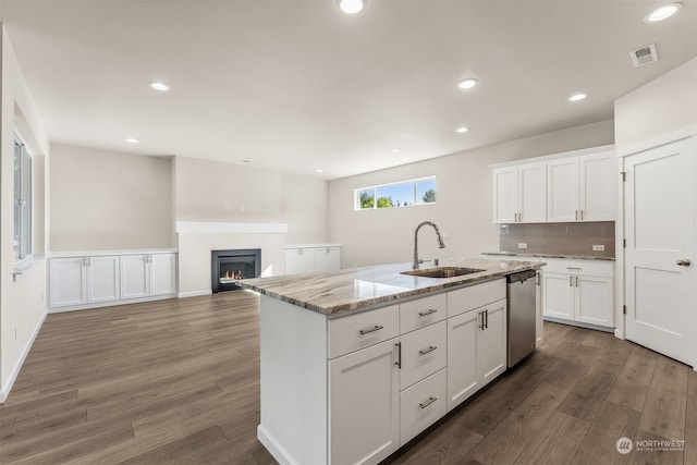 kitchen featuring wood-type flooring, a kitchen island with sink, stainless steel dishwasher, and white cabinetry