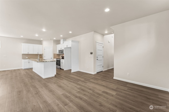 kitchen with a kitchen island with sink, appliances with stainless steel finishes, sink, and light hardwood / wood-style floors