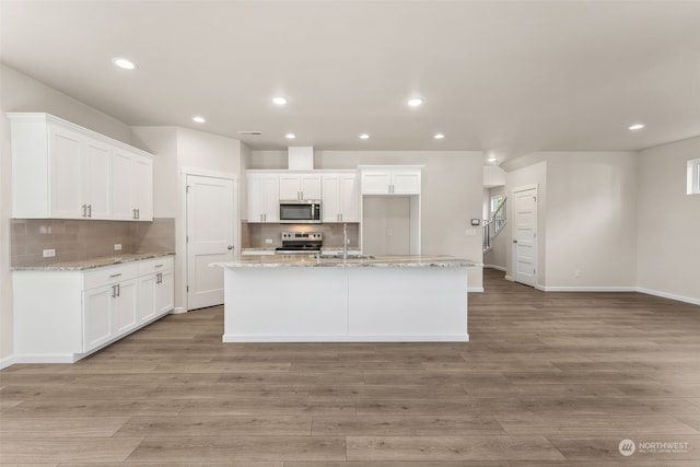 kitchen with appliances with stainless steel finishes, light stone counters, and white cabinets